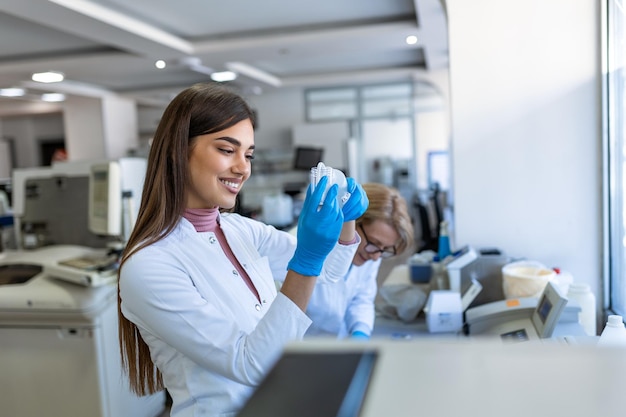 Cientista de pesquisa médica feminina analisa amostras biológicas antes de analisá-las sob o microscópio digital no laboratório de ciências aplicadas engenheiro de laboratório em jaleco branco trabalhando em vacinas e remédios