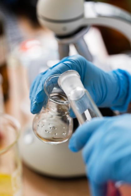 Foto cientista despejando substância de um frasco para outro em um laboratório durante o trabalho de pesquisa