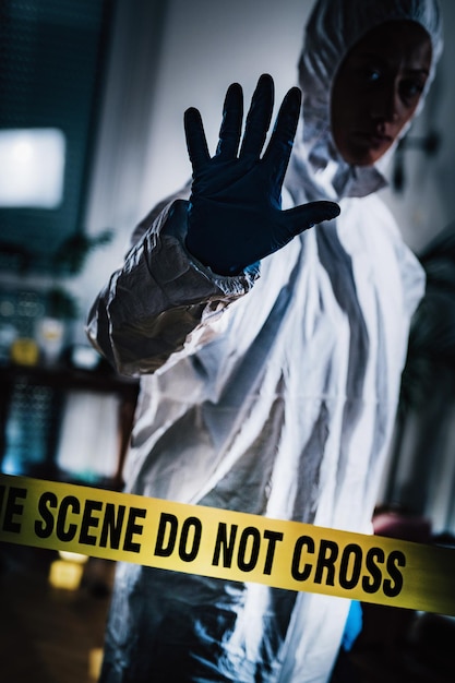 Cientista em traje de proteção com fita adesiva na cena do crime