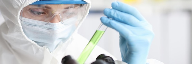 Cientista em traje de proteção detém tubo de ensaio com produtos químicos perigosos líquidos venenosos