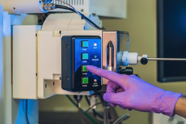 Foto cientista em um laboratório trabalha com um portal de microscópio eletrônico. colocando uma amostra em uma câmara.