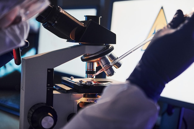 Cientista em uniforme de proteção branco trabalha com coronavírus e tubos de sangue em laboratório