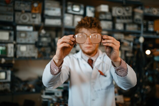 Cientista estranho olha através dos óculos em laboratório. Equipamento de laboratório, oficina de engenharia