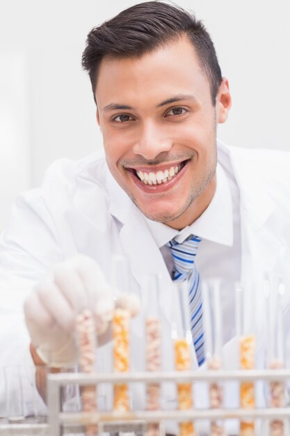 Foto cientista feliz olhando a câmera com tubos de milho e milho