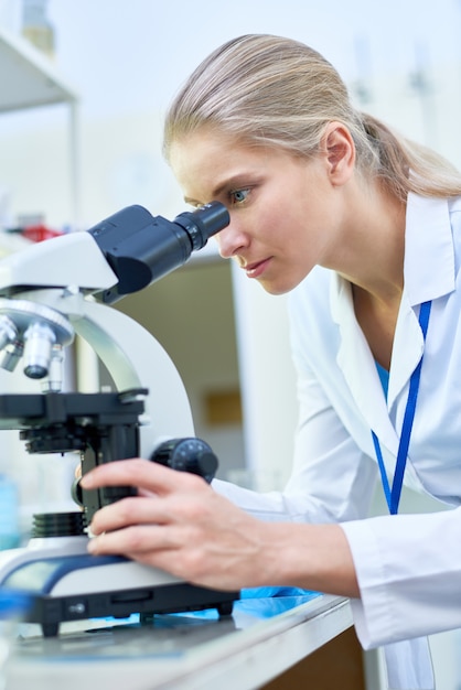 Cientista fêmea que usa o microscópio