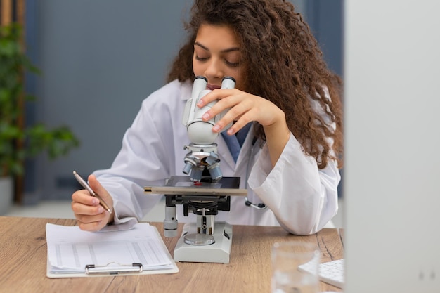 Foto cientista feminina com casaco de medicina trabalha em um laboratório científico