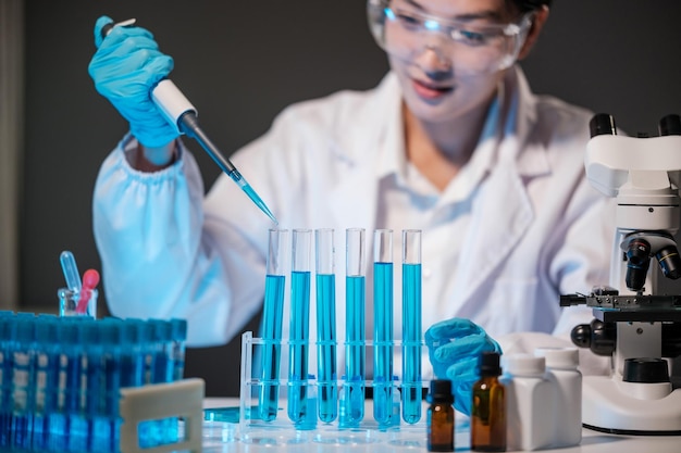 Foto cientista feminina usa micropipetas para encher tubos de ensaio em laboratório moderno