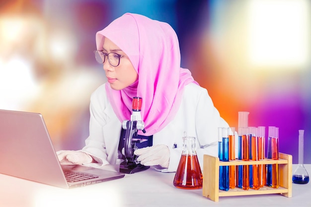 Cientista feminina usando laptop e microscópio