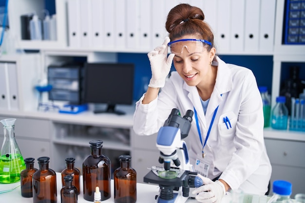 Cientista jovem usando microscópio trabalhando no laboratório