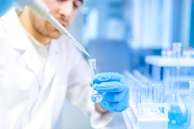 Foto cientista masculino usando ferramenta médica para extração de líquido de amostras em laboratório especial ou sala médica