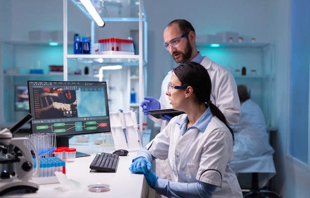 Cientista mulher e médico estudando especialização em vírus no laboratório de medicina, trabalhando com equipamentos de tecnologia profissional