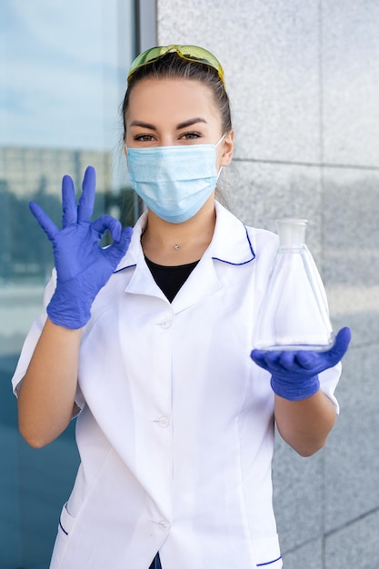 Cientista oriental de cabelos escuros com máscara protetora de vestido de médico