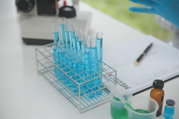 Foto cientista ou médico em casaco de laboratório trabalhando em laboratório biotecnológico equipamento de microscópio para pesquisa com reagentes de mistura em frasco de vidro em laboratório clínico