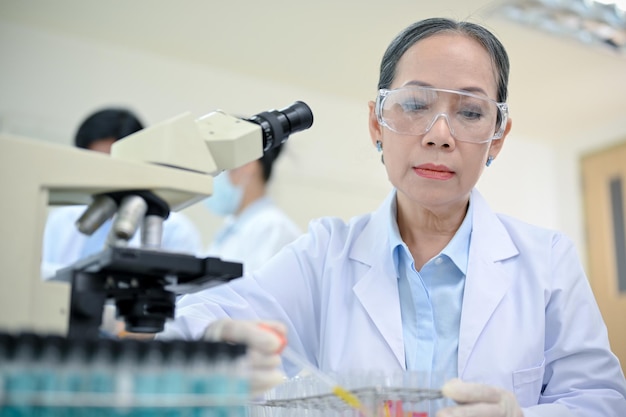 Cientista ou pesquisadora asiática envelhecida concentrando-se em seu projeto médico no laboratório