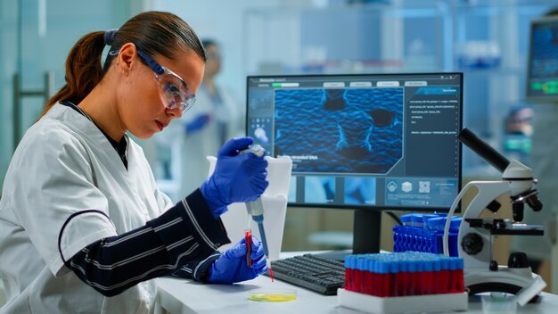 Cientista pesquisador usando micropipeta para extrair amostra de sangue em placa de Petri, analisando a reação química em laboratório. Médico examinando a evolução do vírus usando ferramentas de alta tecnologia e química
