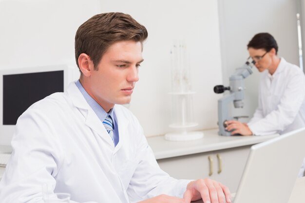 Foto cientista que trabalha atentamente com o laptop