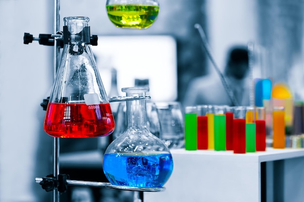 Cientista que trabalha com reação química no laboratório de química. close-up do cientista fazendo pesquisa em laboratório, química molecular no fundo do laboratório de ciências de química azul