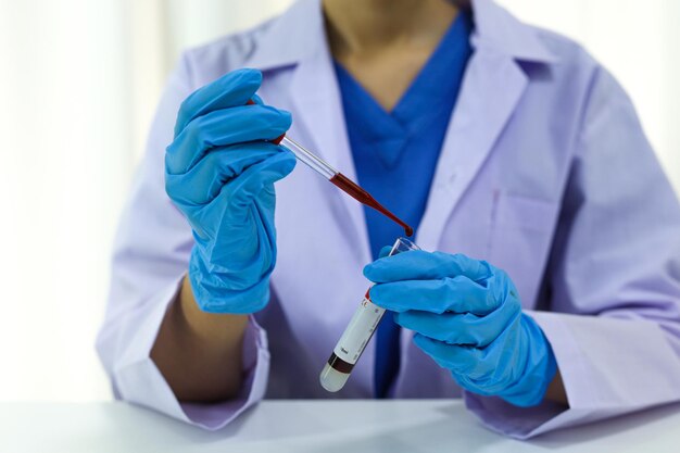 Foto cientista segurando tubo de amostra de sangue infectado com coronavirus covid-19 teste de dna do sangue no laboratório com tubos de coleta de amostras de sangue e seringa pesquisa de vacina contra coronavirus covid-19