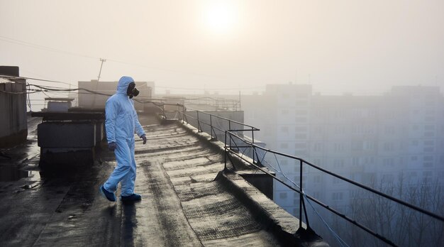 Cientista trabalhador vestindo macacão de proteção e máscara de gás fazendo testes ecológicos no telhado