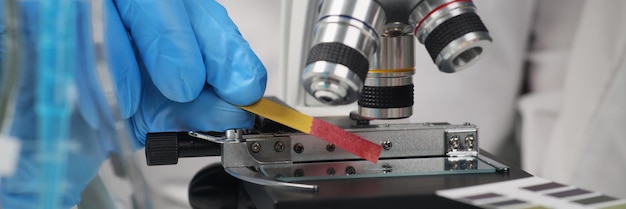 Cientista uniformizado faz teste de acidez com papel indicador em amostra profissional de laboratório