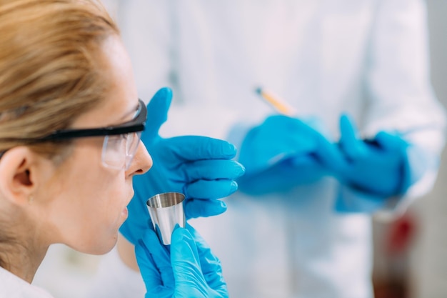Cientistas femininas olfativas cheirando uma amostra no copo de teste