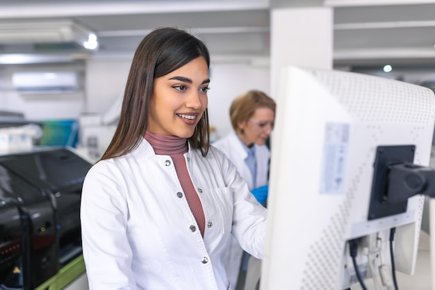 Cientistas femininas programam equipamento médico com computador pessoal Equipe de profissionais trabalhando em laboratório moderno de pesquisa farmacêutica