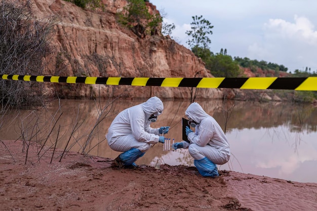 Cientistas ou biólogos vestindo uniformes de proteção trabalhando juntos na análise da água Engenheiros ambientais inspecionam a qualidade da água numa área perigosa