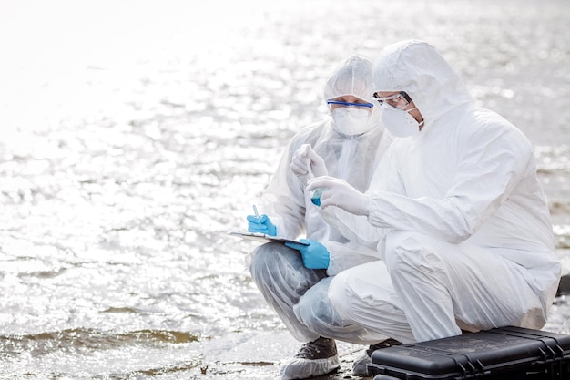 Cientistas ou biólogos vestindo uniformes de proteção trabalhando juntos na análise da água xA