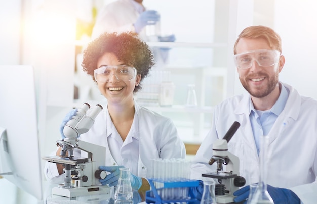 Cientistas sorridentes olhando para os braços da câmera cruzados em laboratório