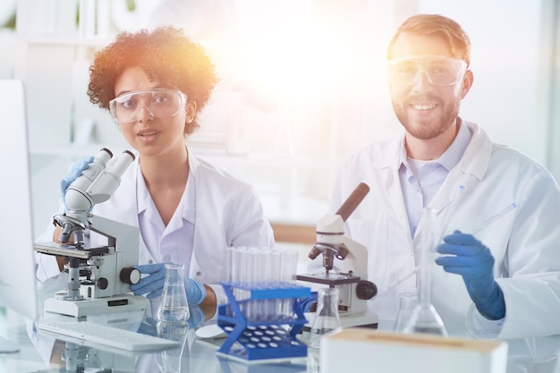 Cientistas sorridentes olhando para os braços da câmera cruzados em laboratório