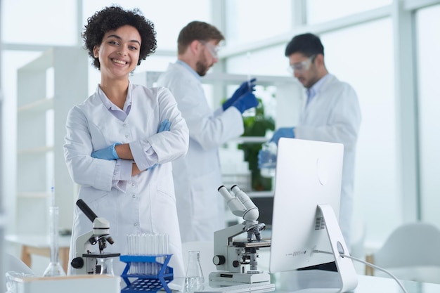 Cientistas sorridentes olhando para os braços da câmera cruzados em laboratório