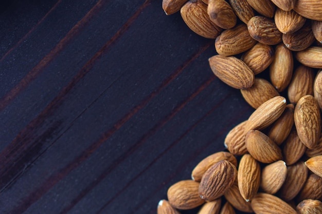 Cierra las almendras en la mesa de madera oscura. Comida vegetariana de proteína de salud orgánica. Espacio de copia de fondo