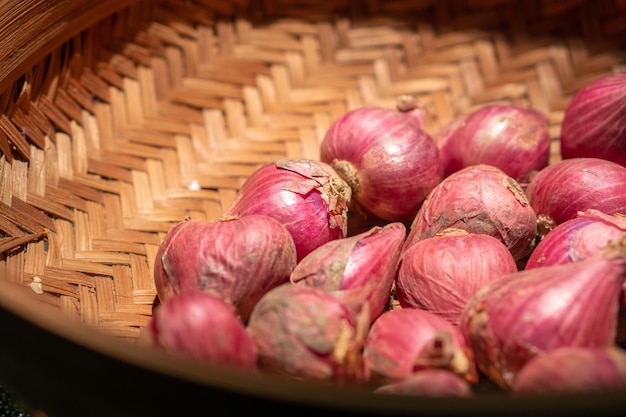 Foto cierra cebollas rojas frescas en una cesta de mimbre para sazonar la cocina indonesia