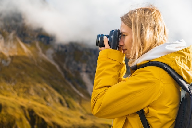 Cierra a una chica bonita tomando fotos de montañas en los Alpes italianos con una cámara retro