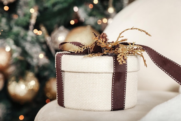 Cierra la elegante caja de regalo blanca en el fondo interior decorado con Navidad en la sala de estar con el árbol de Año Nuevo