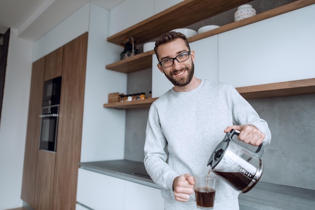 Cierra a un hombre sirviéndose una taza de café matutino