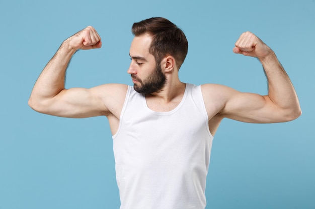 Cierra a un joven barbudo de 20 años de edad con una piel perfecta y una camisa blanca aislada en un fondo de pared azul pastel, retrato de estudio. Concepto de procedimientos cosméticos para el cuidado de la piel. Simulacros de espacio de copia