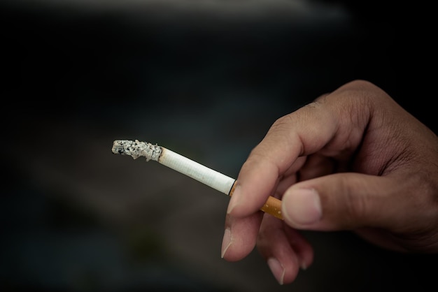 Cierra la mano de un hombre guapo asiático sosteniendo un cigarrillo