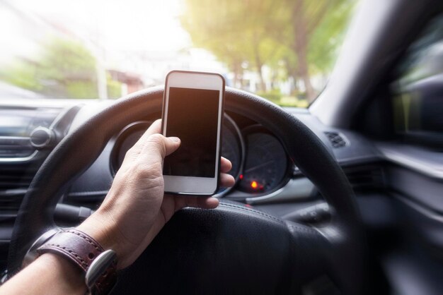 Cierra la mano del hombre usando el teléfono inteligente mientras está conduciendo el coche