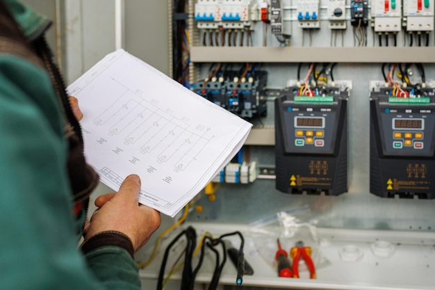 Foto cierra la mano del ingeniero o electricista que trabaja revisando el sistema eléctrico con una tableta en la fábrica