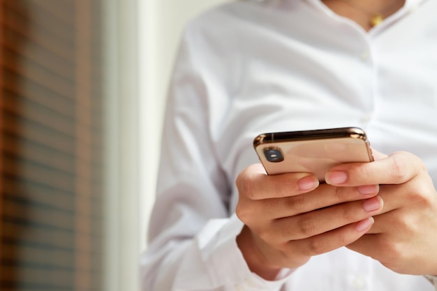 Cierra la mano de una mujer joven viendo un mensaje en un teléfono inteligente móvil durante el descanso usando teléfonos celulares para comunicarse en el mundo en línea con una pantalla negra en blanco o vacía