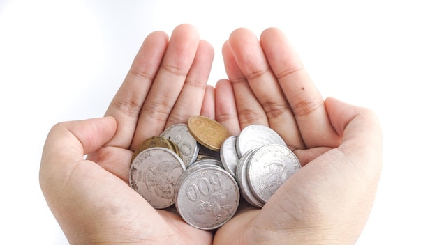 Cierra las monedas indonesias en las manos El enfoque selectivo da una pila de monedas con ambas manos