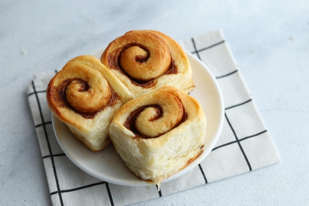 Cierra el pan de rollo de canela en un plato blanco para el desayuno.