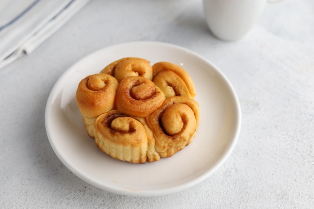 Cierra el pan de rollo de canela en un plato blanco para el desayuno.