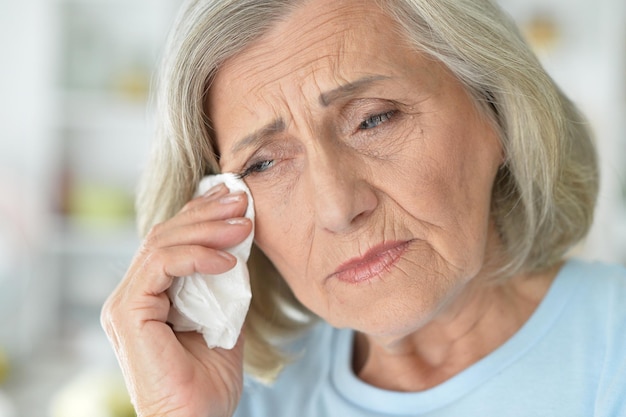 Cierra el retrato de una anciana triste y enferma posando en casa