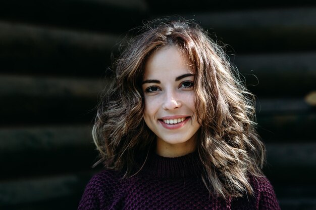 Cierra el retrato de una hermosa joven sonriente feliz en un fondo oscuro al aire libre