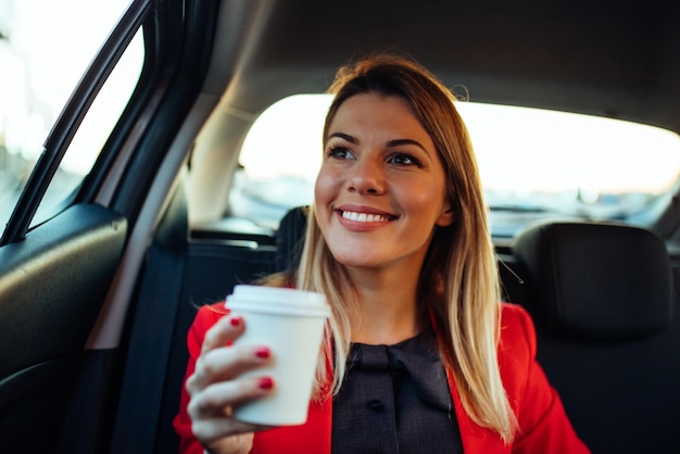 Cierra el retrato de una hermosa joven sosteniendo una taza de café en el auto