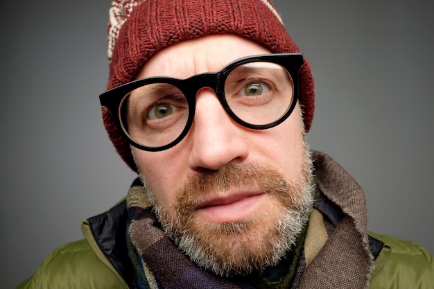 Cierra el retrato de un hombre europeo de mediana edad con un divertido sombrero cálido y gafas que notan la cámara oculta