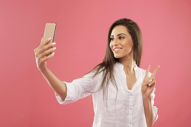 Cierra el retrato de una joven hermosa y elegante mujer haciendo selfie usando sus propias sonrisas de smartphone