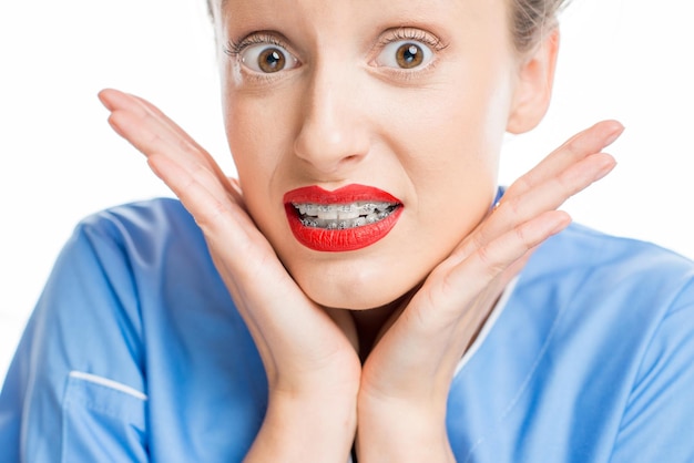 Cierra el retrato de una mujer con frenos dentales en el fondo blanco. Mujer preocupada por una nueva sonrisa con frenillos